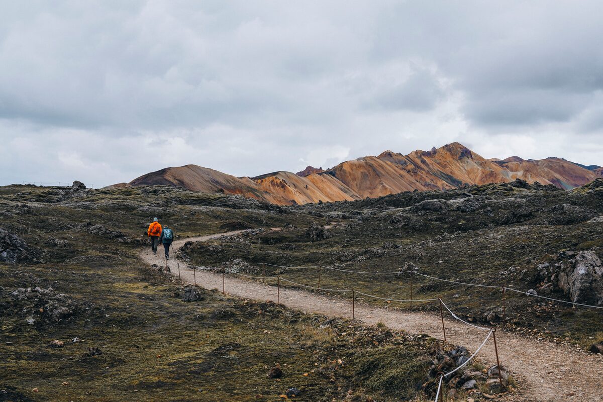 Duo walking through Landmannalaugar hiking pathway through geothermal area