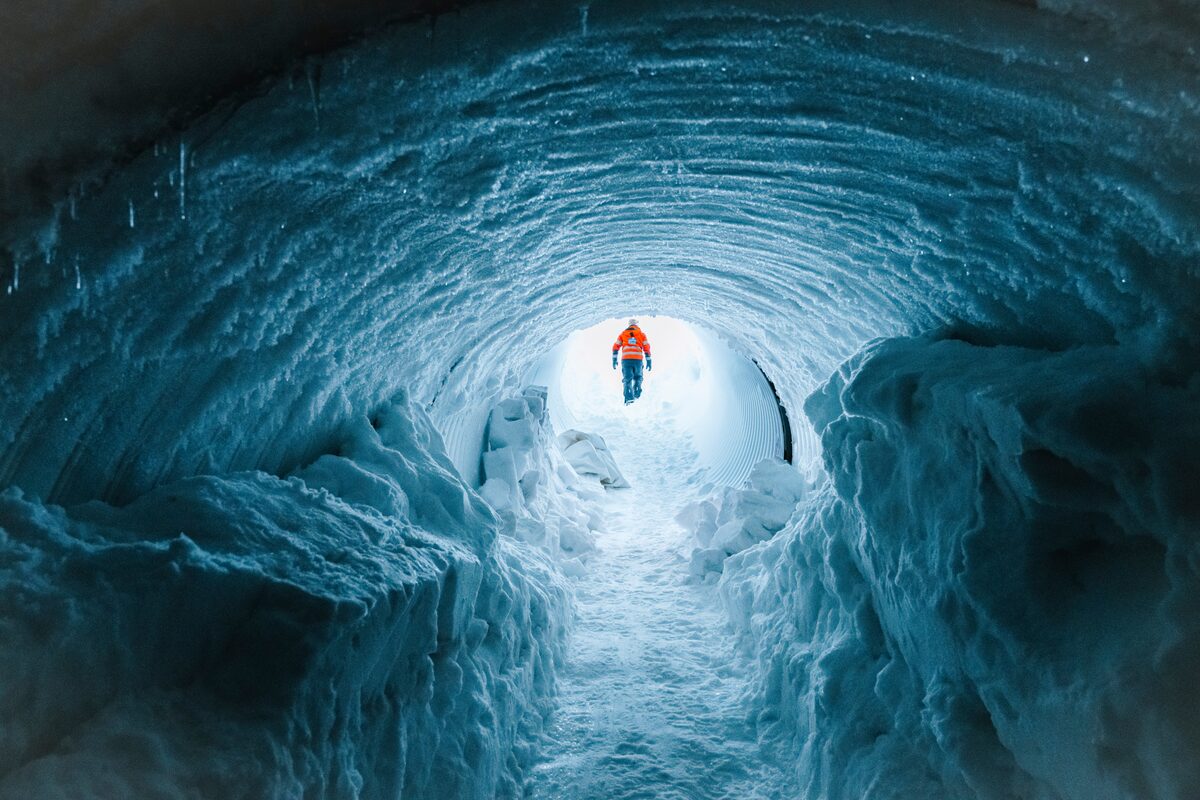Man in orange jacket walking out of ice tunnel at Langjokull glacier 