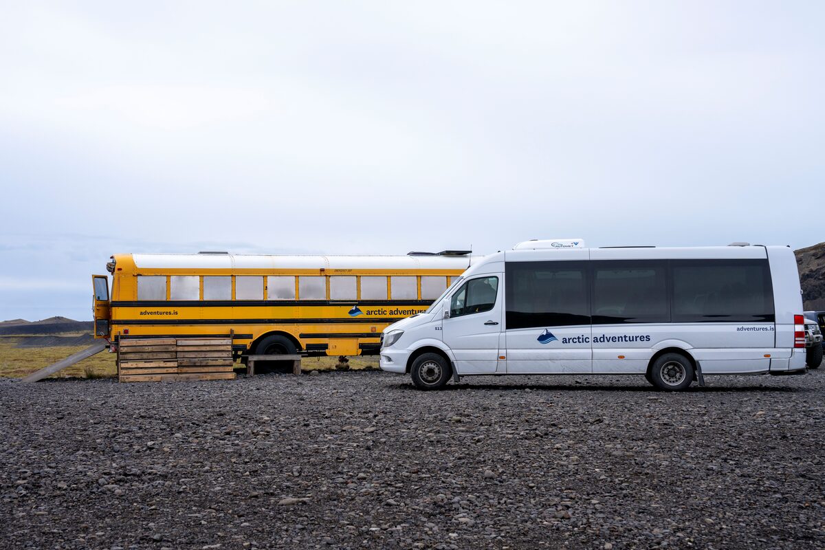 Solheimajokull parking, arctic adventures white van and school bus of tour equipment 