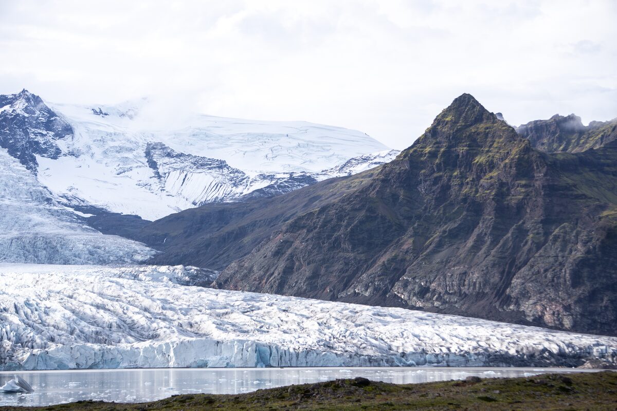 Huge glacial lagoon leading to mountains large moss covered mountain on right side 