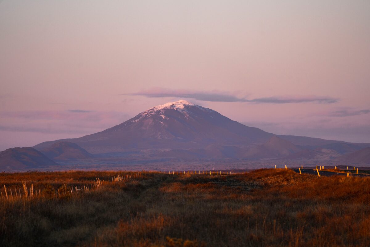 Beautiful purple hue sunset volcano landscape with autumn grass