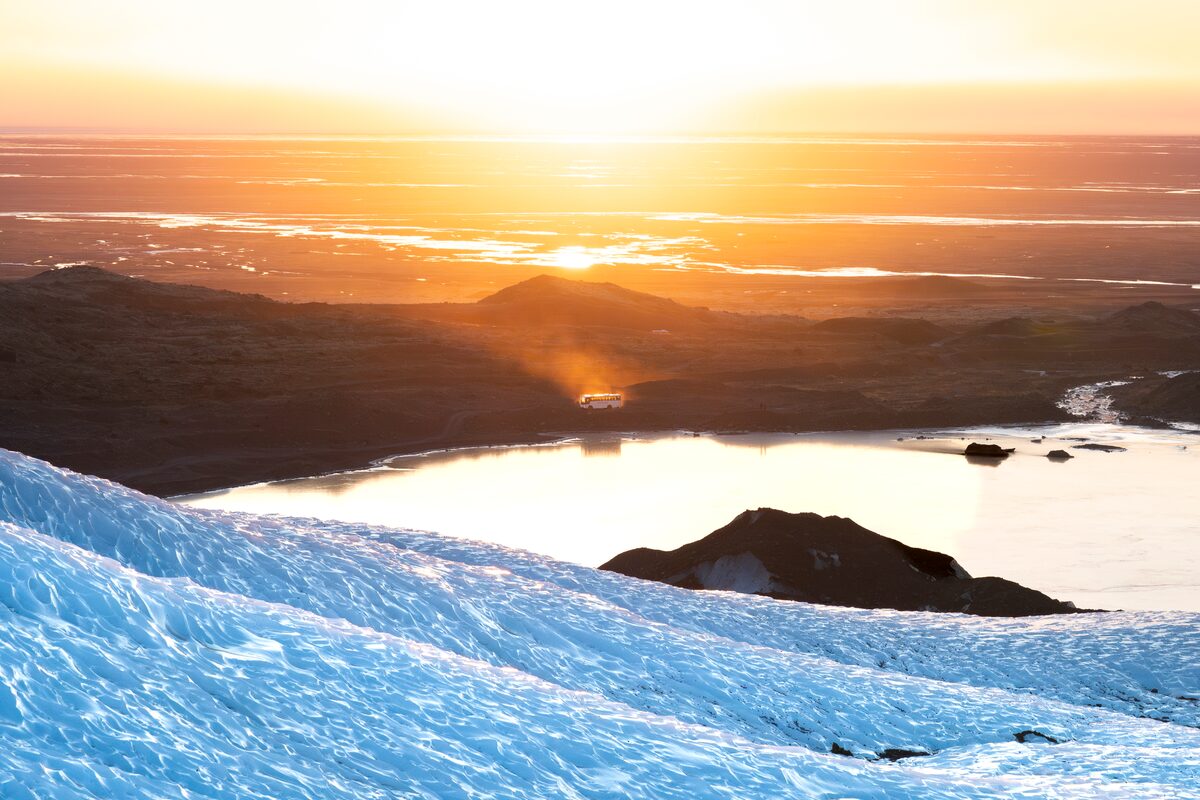 Bus in distance views from Falljokull Glacier looking down to sunset
