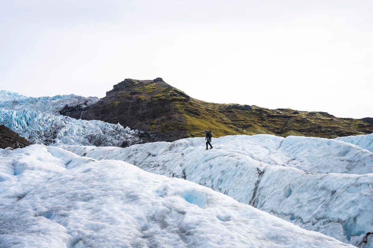 Tourist hiking up huge crevasses in glacier at Falljokull