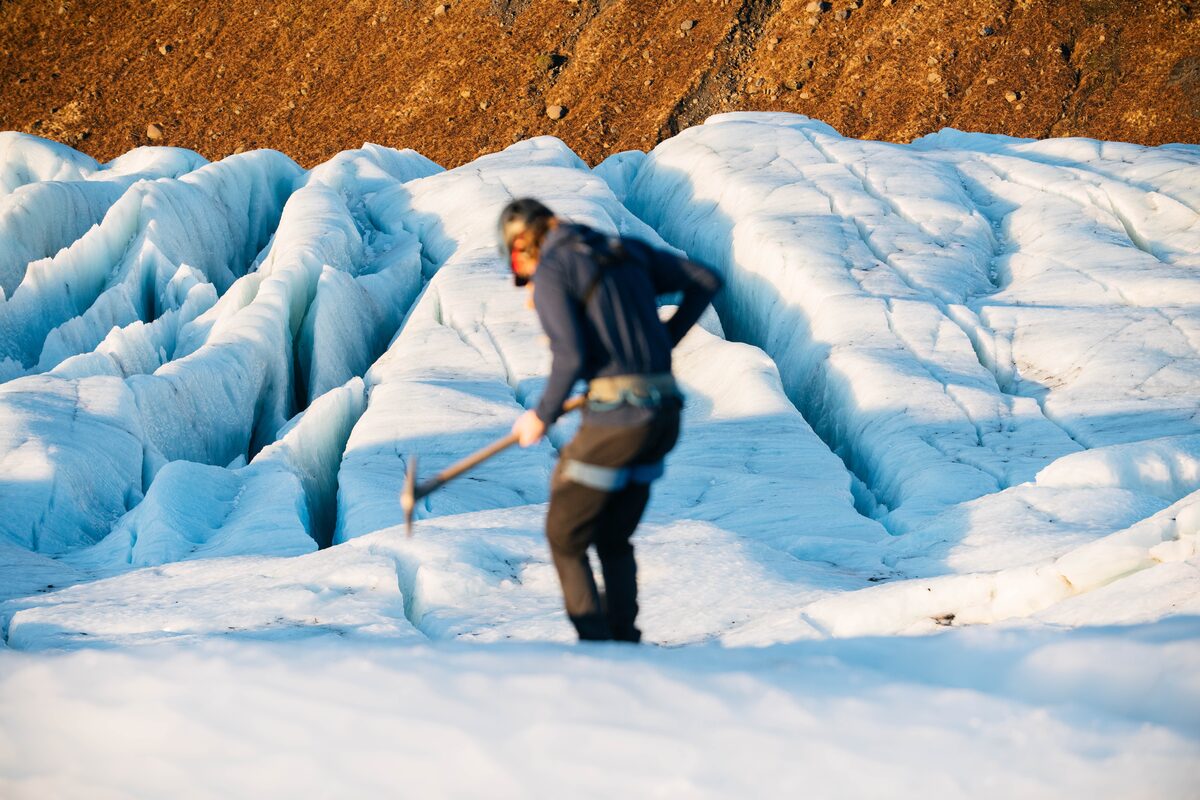 Tourist with ice pick standing on large crevasses at Falljokull glacier 
