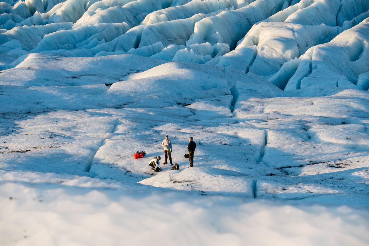 Tourists in distance standing on vast landscape of glacier crevasses