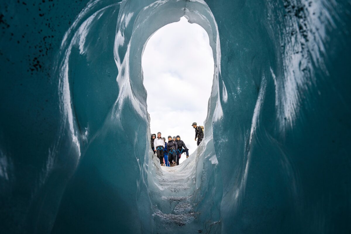 Tourists peeking through gap in glacier crevasses posing for group photo 