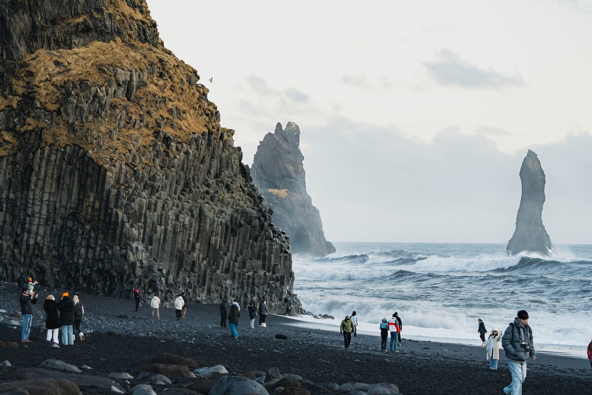 Group of tourists standing on black sand beach in Iceland 