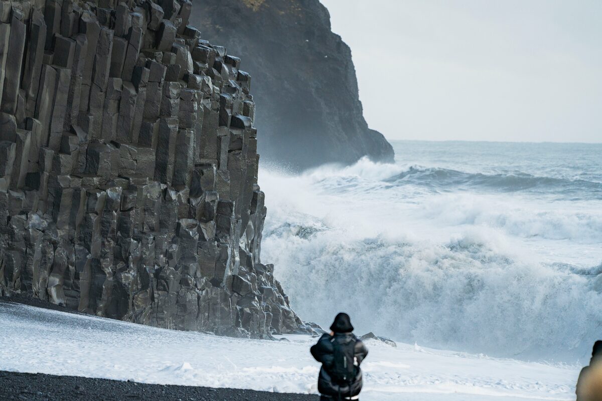 Tourist photographing Reynisfjara black sand beach basalt columns
