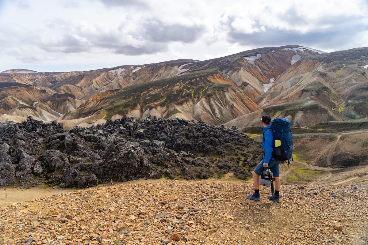 A man is overviewing scenery of the mountains on his hiking trail in Iceland.