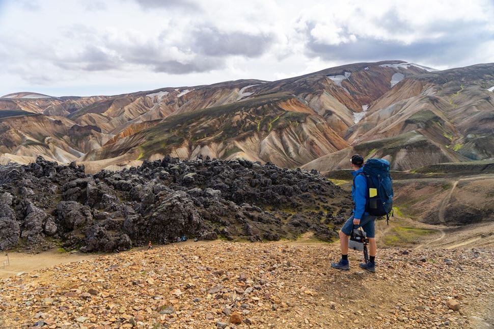 A man is overviewing scenery of the mountains on his hiking trail in Iceland.