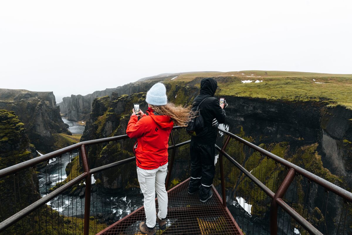 Young female taking photo on phone of Fjardargljufur Canyon