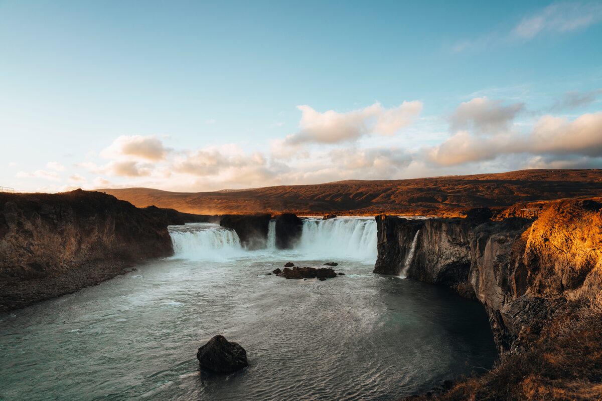 Godafoss duo of waterfalls flowing into lake during sunset