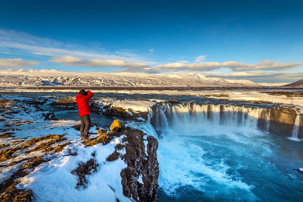 Photographer standing at viewpoint taking photo of Godafoss falls
