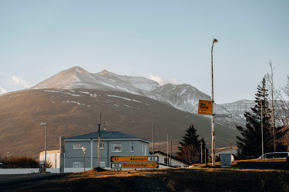North Dalvik building in front of mountain and direction signs next to road