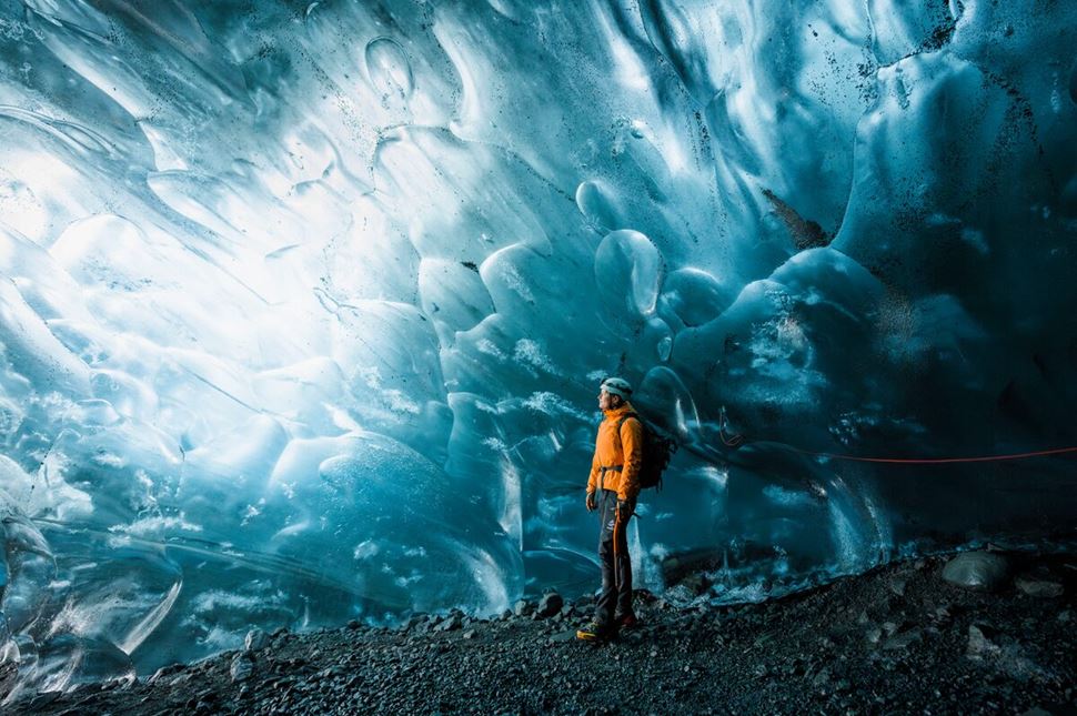 Male tourist posing for photo inside crystal ice cave with ice pattern walls