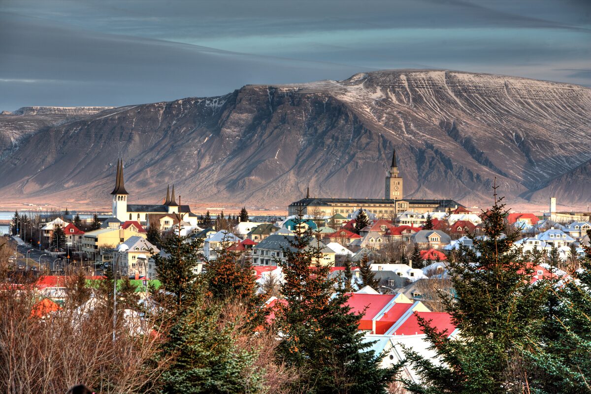 Reykjavik's roofs and churches viewed from the top and a mountain behind.