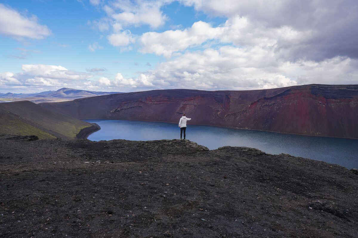 Tourist posing in front of Ljotipolliur lake standing on edge 