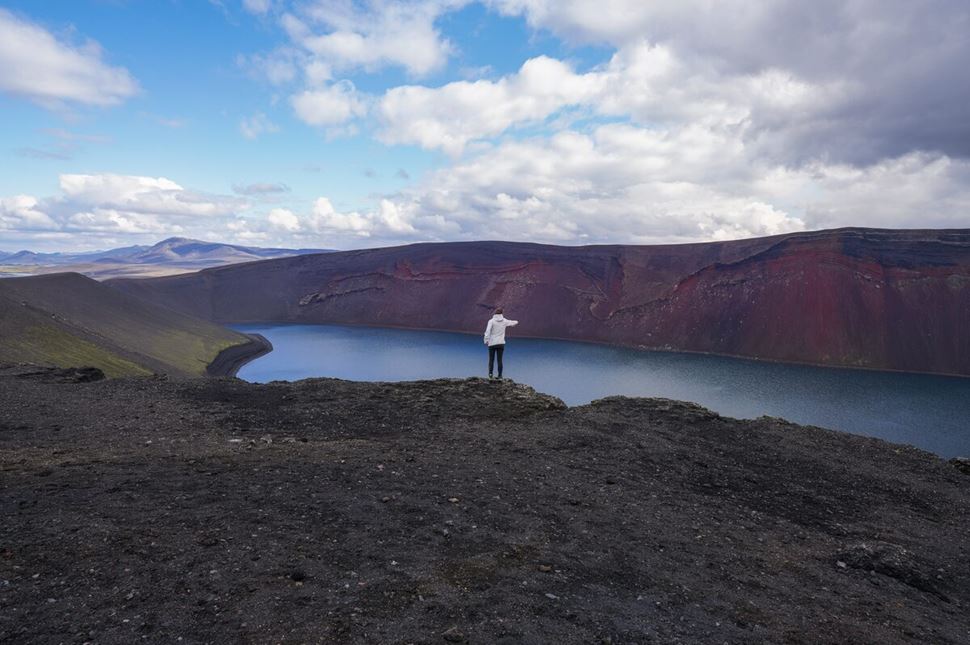 Tourist posing in front of Ljotipolliur lake standing on edge