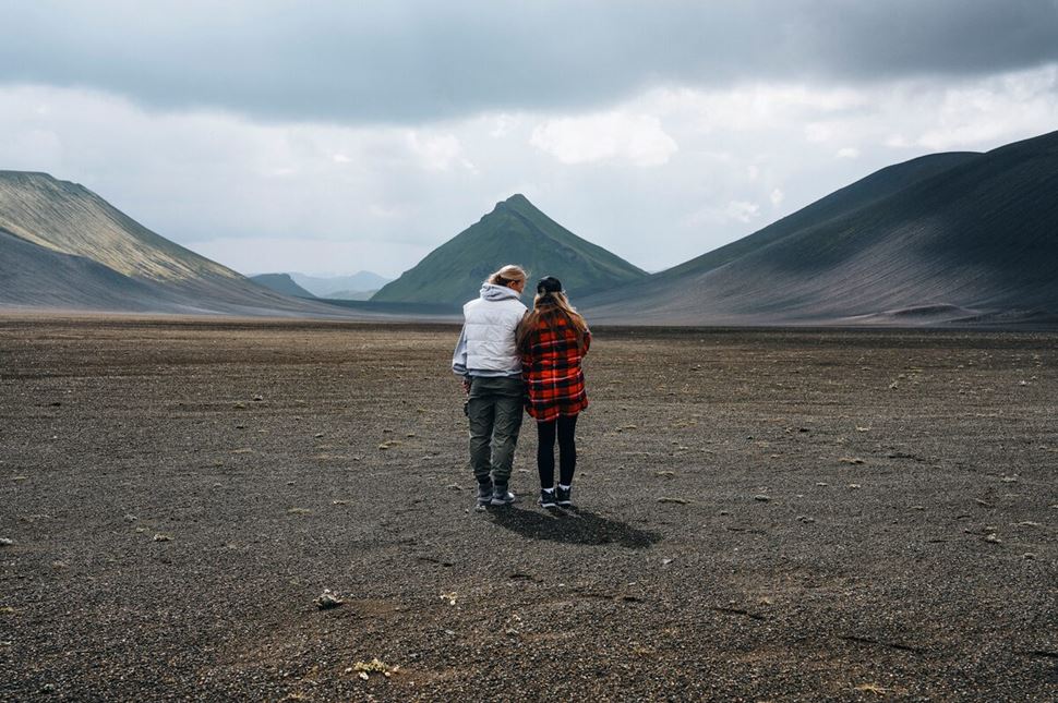 Couple hiking in open space at Landmannalaugar towards green mountain Maelifell