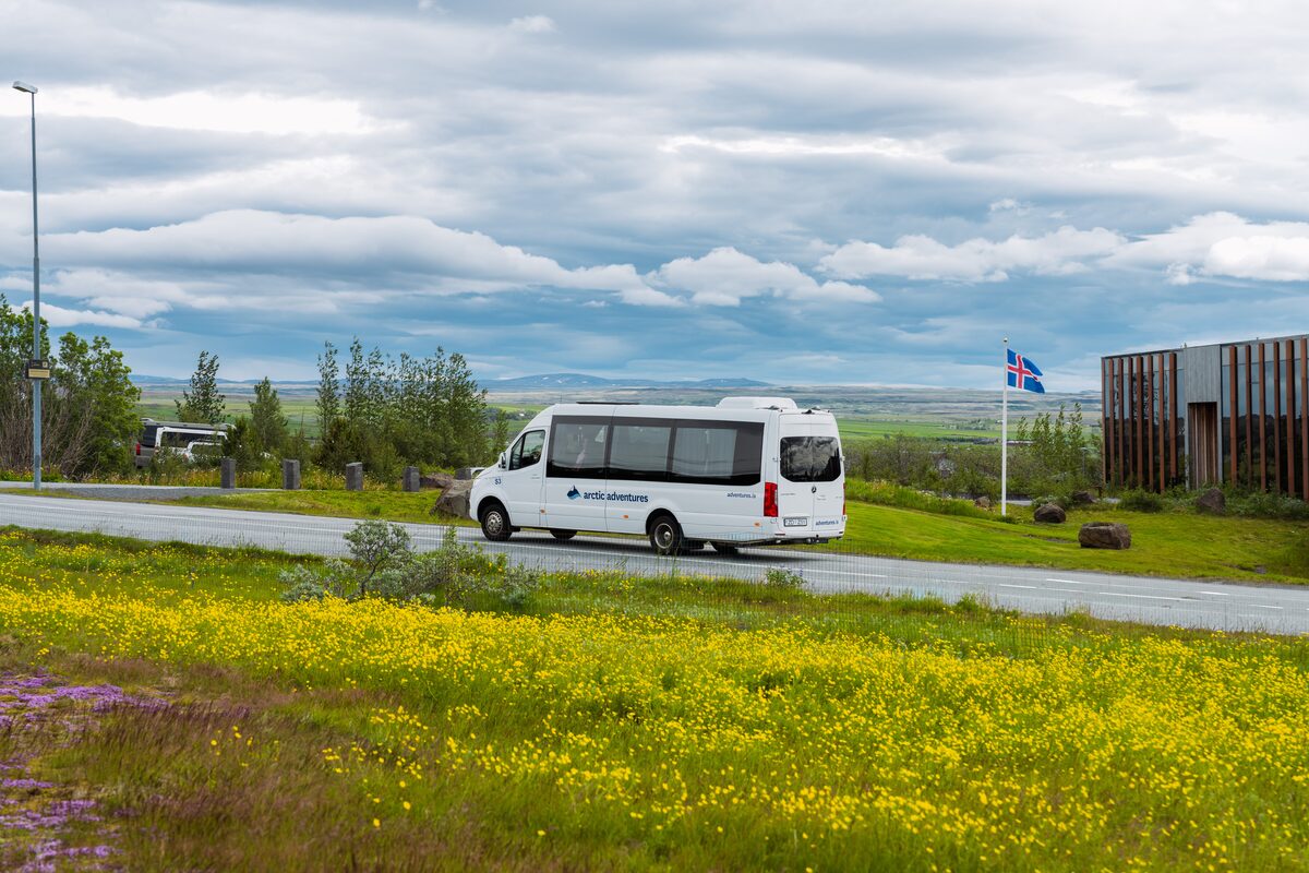 Arctic Adventures white tour van driving through scenic route in golden circle in spring
