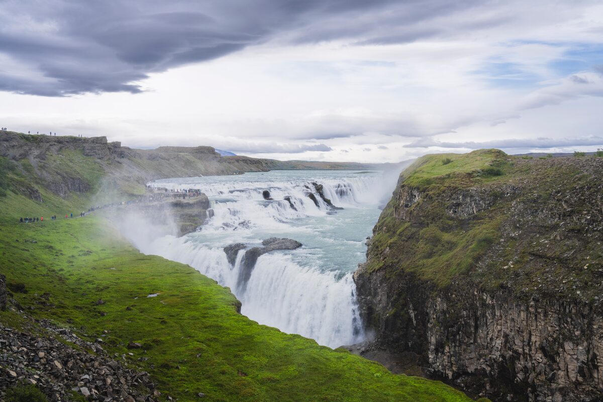 Golden Circle route gullfoss waterfall surrounded by green grass and grey skies in spring