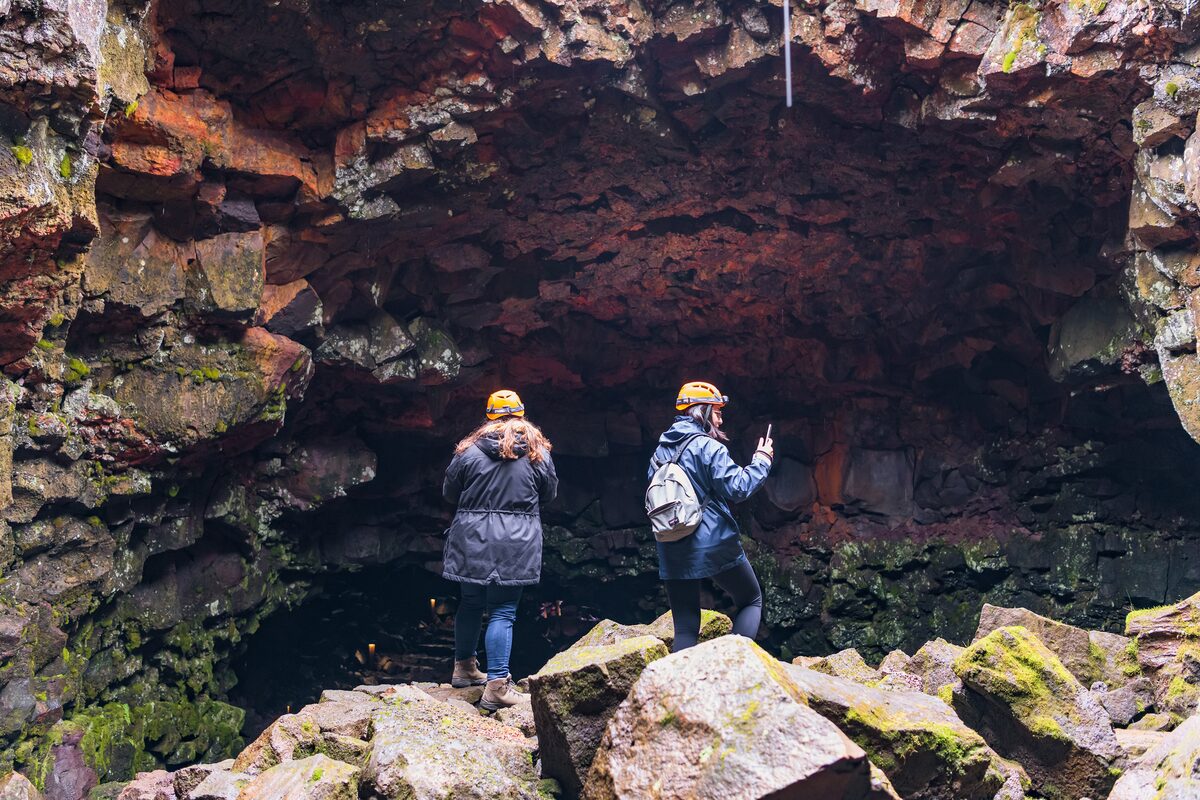 Two tourists standing outside entrance to Raufarhólshellir lava tunnel 
