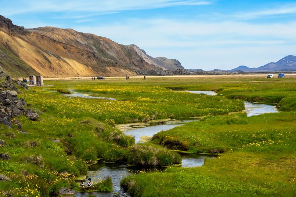 Landmannalaugar natural hot springs situated close to camp site in spring with blossoming field