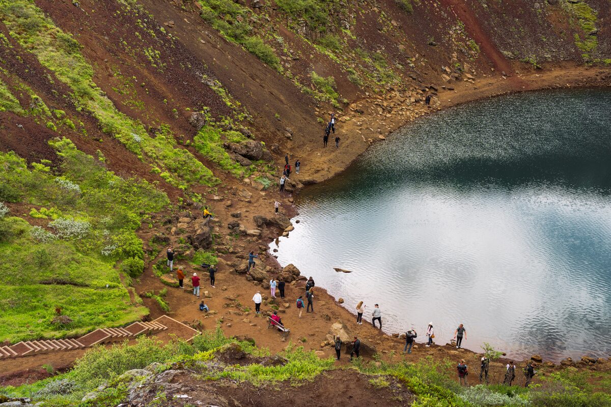 Tourists standing around edge of Kerid crater lake close up view 