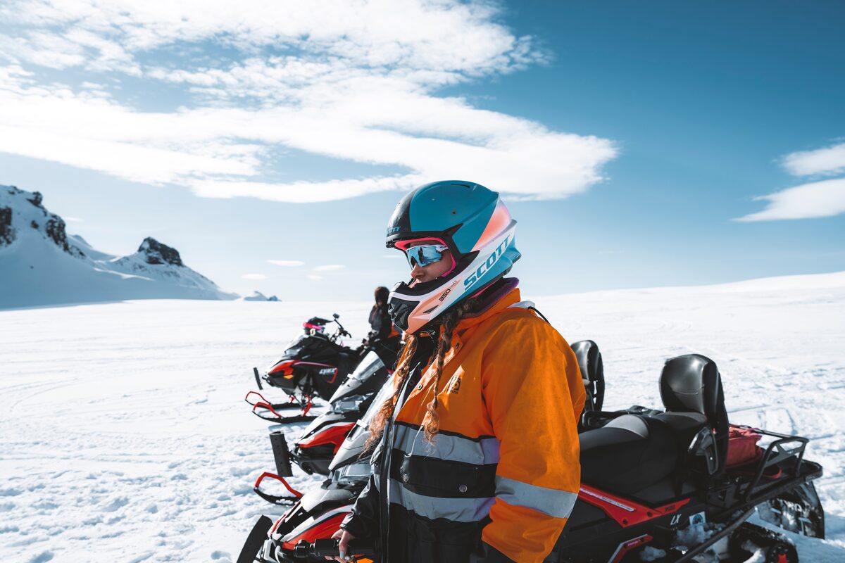 Close up of tourist standing in front of Langjokull glacier in orange snowmobiling safety gear