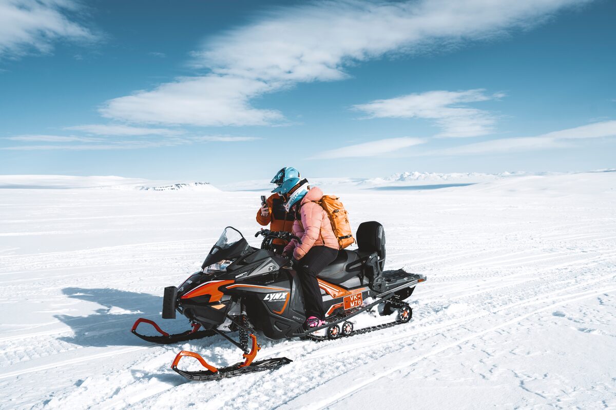 Two friends of snowmobiles riding close together across Langjokull