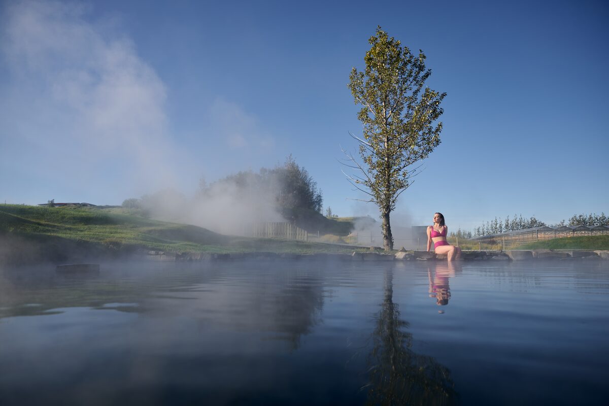 Lady sitting at edge of Secret Lagoon pool relaxing in bikini during summer.