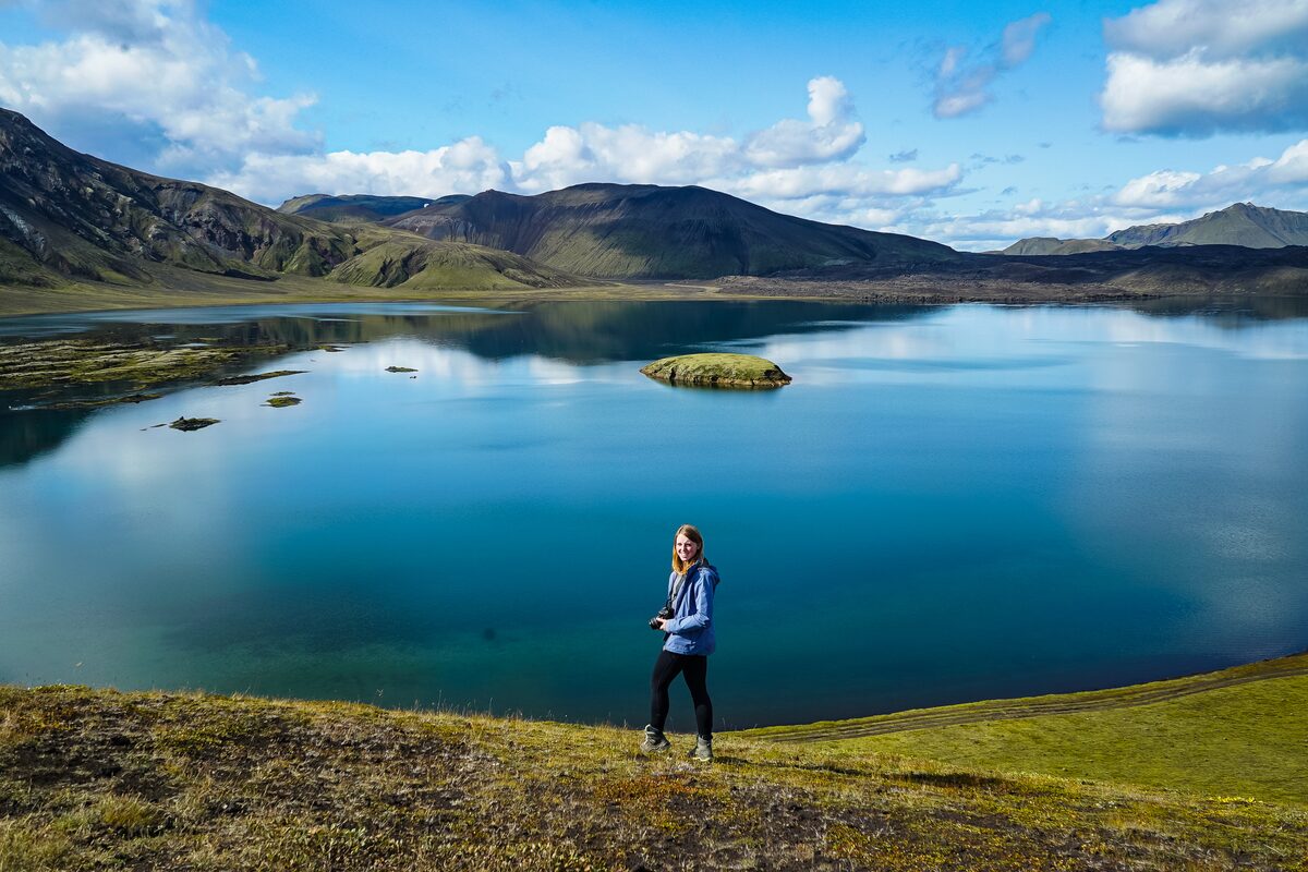 Lady posing for photo at Landmannalaugar in front of Frostastaðavatn lake in summer.
