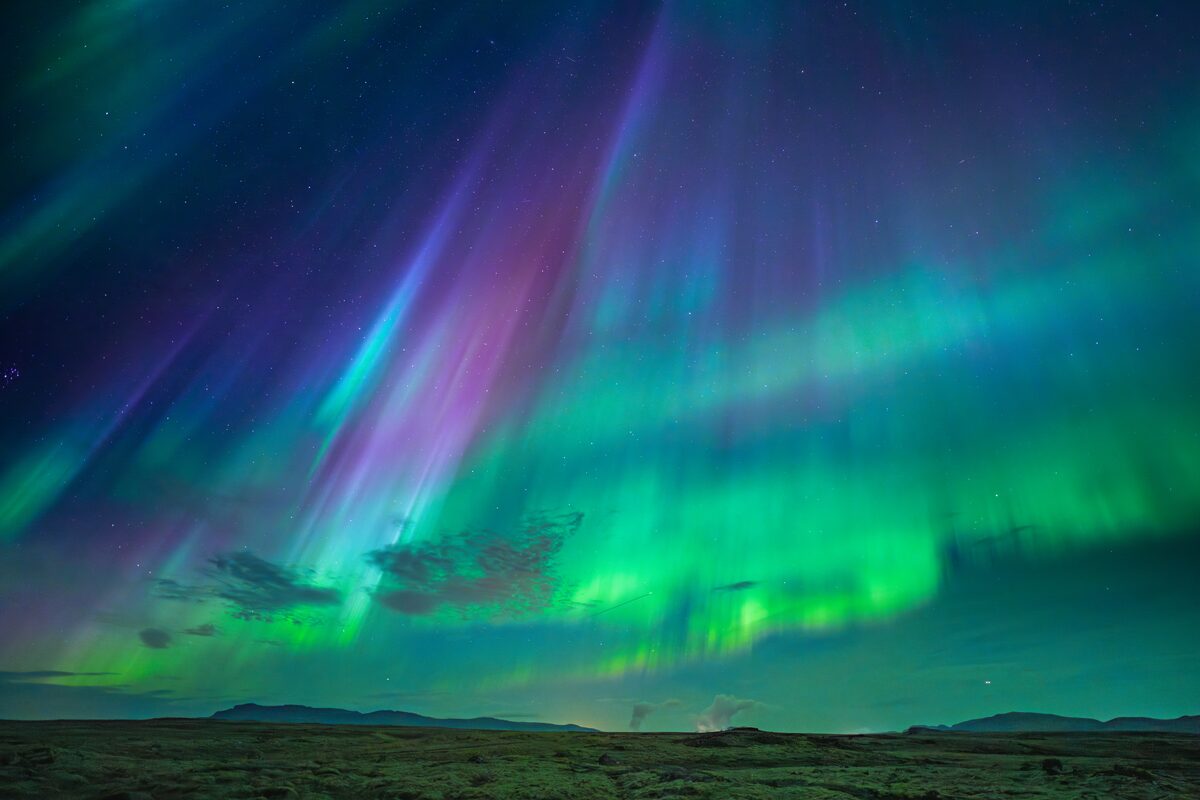 Brightly multi colored northern lights in sky at Nesjavallaleid Iceland.