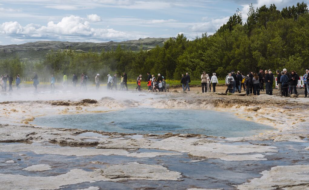 Crowd gathers in Golden Circle Iceland in early summer to watch Geysir erupting.