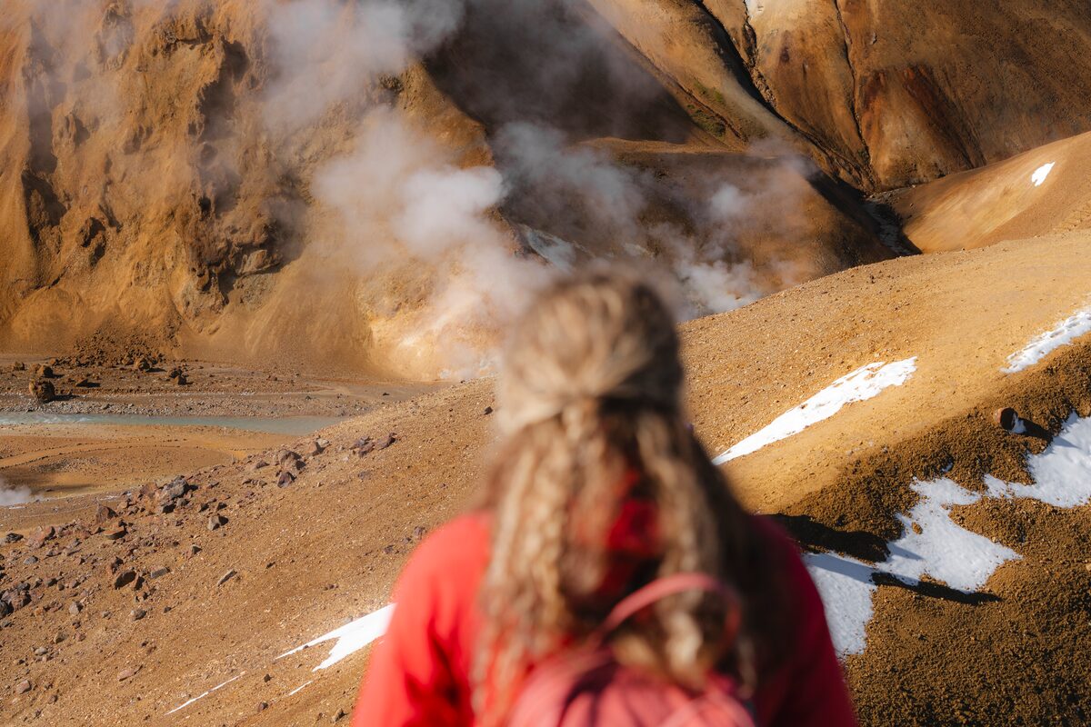 A woman looking at a steam rising in the Kerlingarfjöll Mountain range.