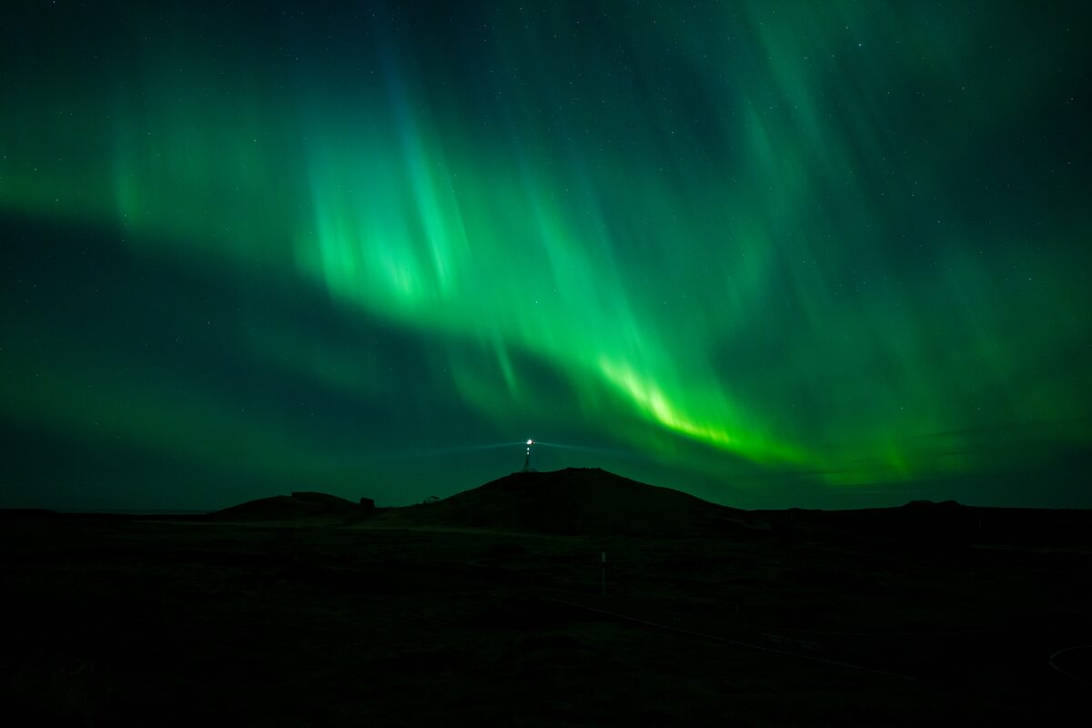 Person posing for photo underneath northern lights.