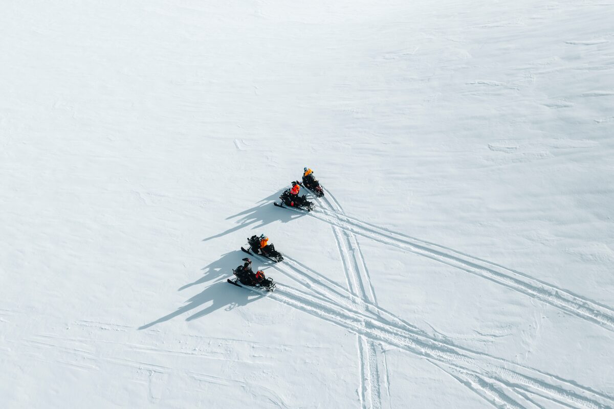 Birds eye view of four snowmobiler leaving tracks in the snow at Langjokull.