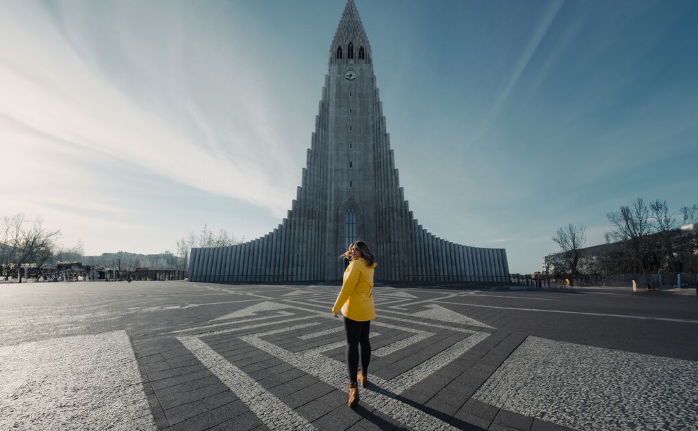 Female walking across city center square towards Reykjavik church during summer.