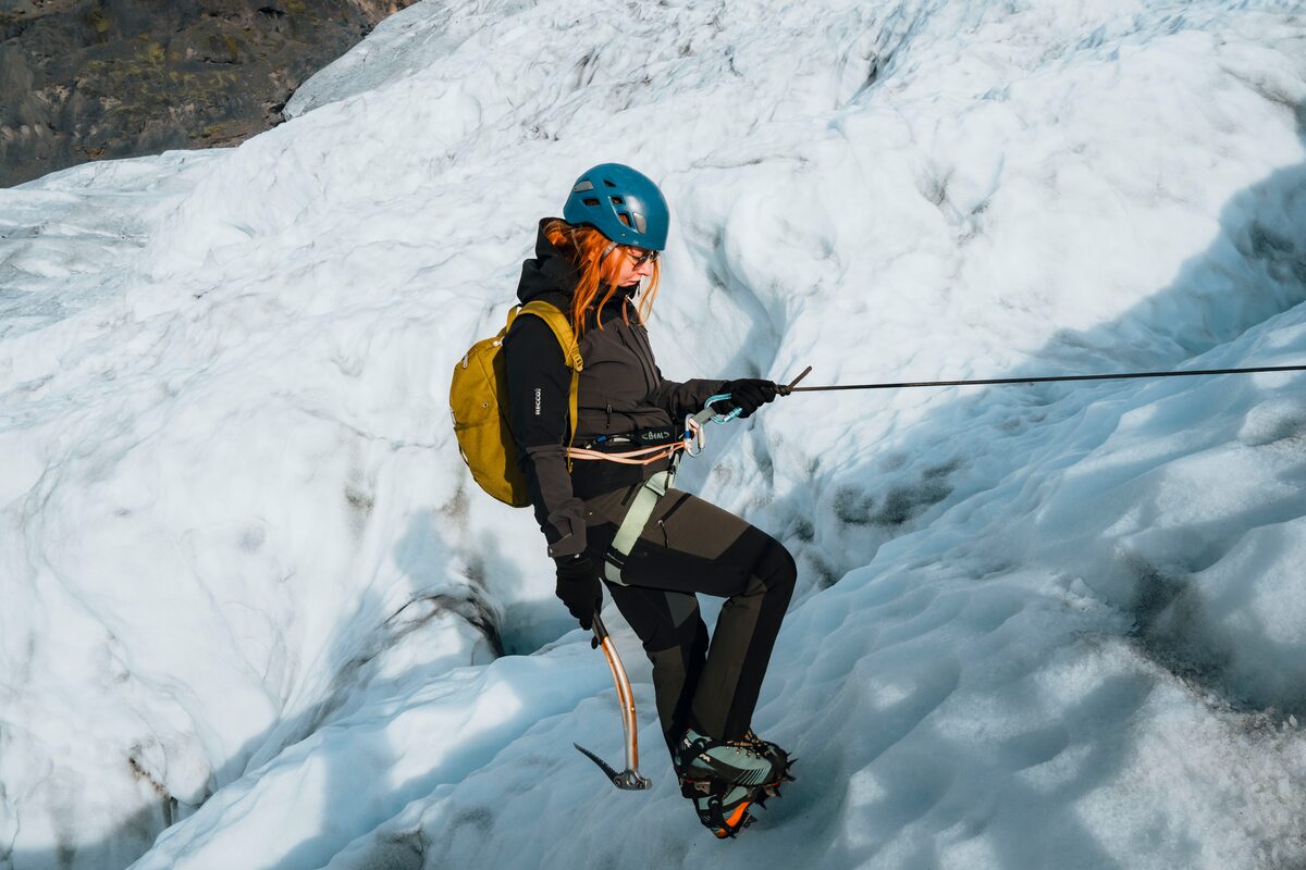 Tourist ice climbing large ice formations at Vatnajokull glacier during spring.