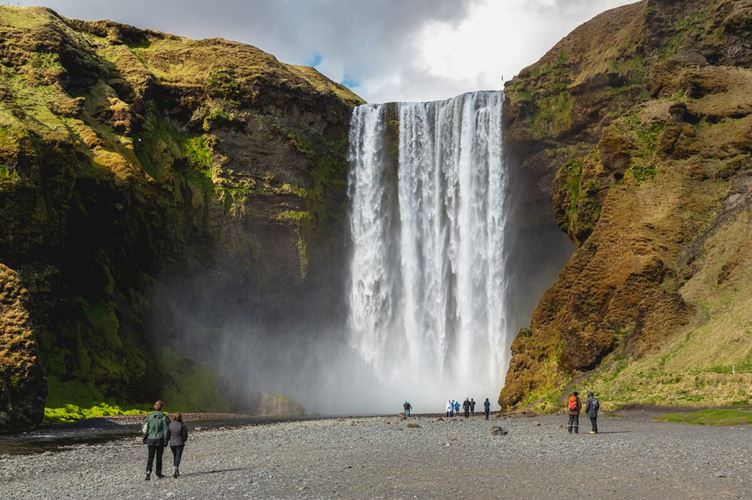 Tourists walking towards the great Skogafoss waterfall in Iceland during spring.