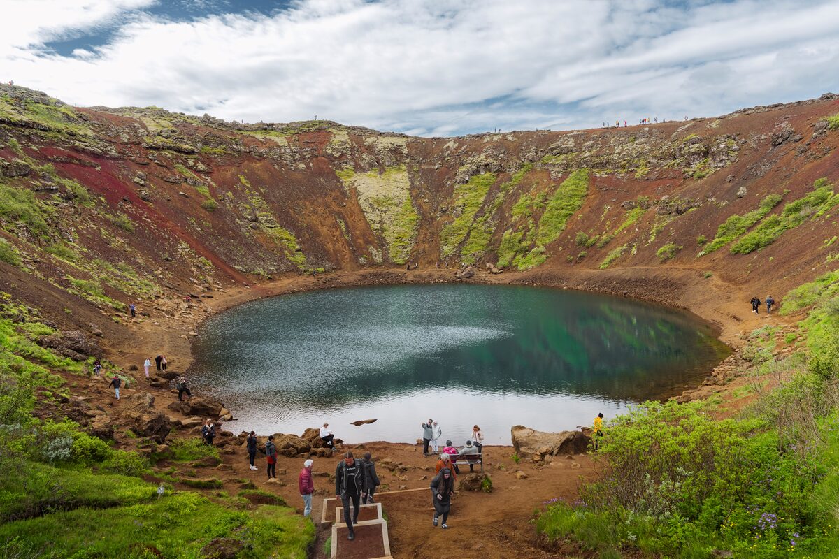 Small crowd at Kerid standing inside crater by crater lake during spring.