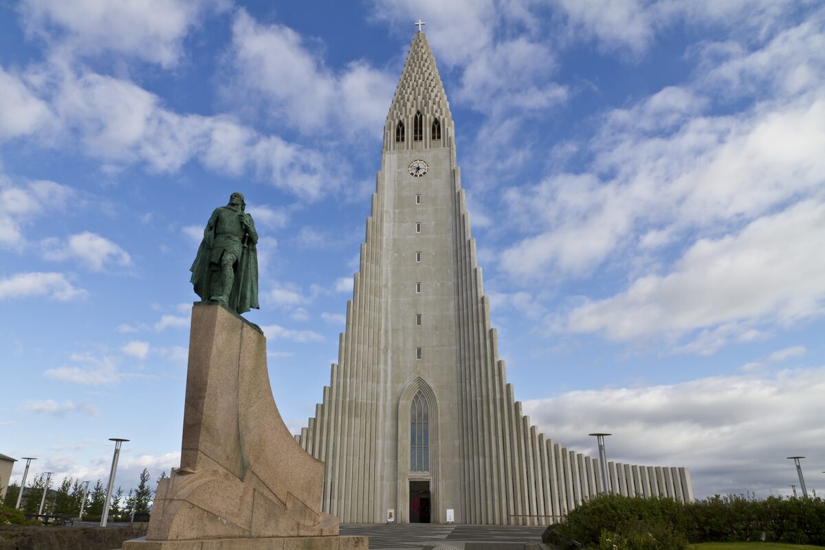 Hallgrímskirkja church and the statue of Leif Erikson in Reykjavík, Iceland, framed by dramatic clouds in the sky.