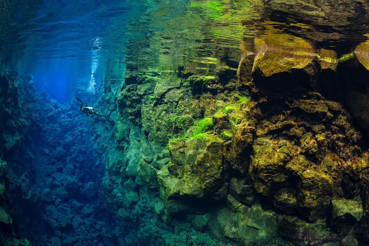 Diver at Silfra fissure amongst the beautiful under water colors between two continents.