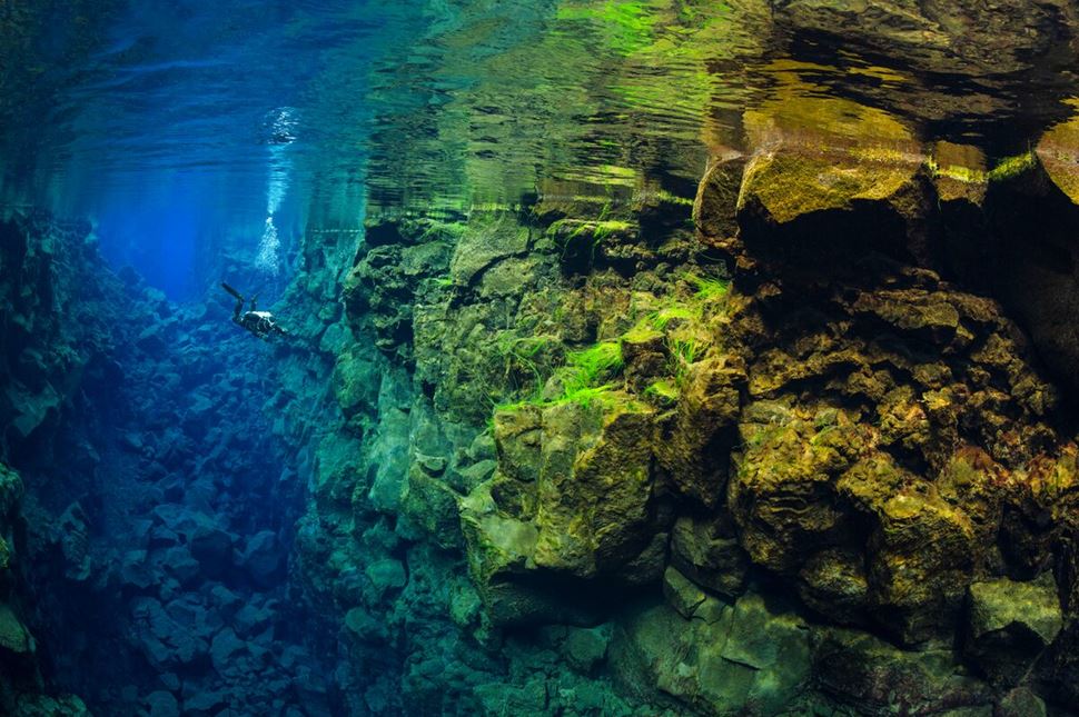 Diver at Silfra fissure amongst the beautiful under water colors between two continents.