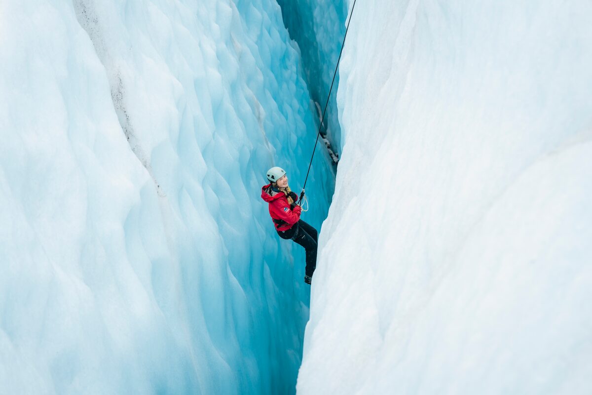 Female ice climbing up large steep glacier crevasse at Falljokull in spring.