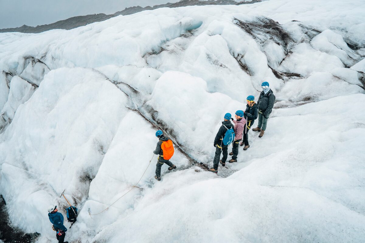 Small group of people hiking across Falljokull glacier in spring.