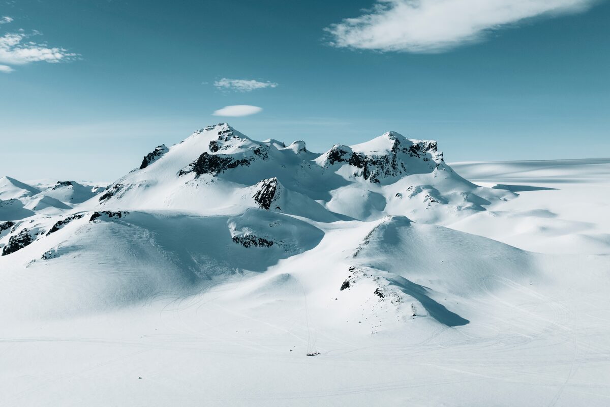 A wide, snowy expanse of Langjökull Glacier in Iceland, with smooth white ice stretching across the landscape beneath a bright blue sky.