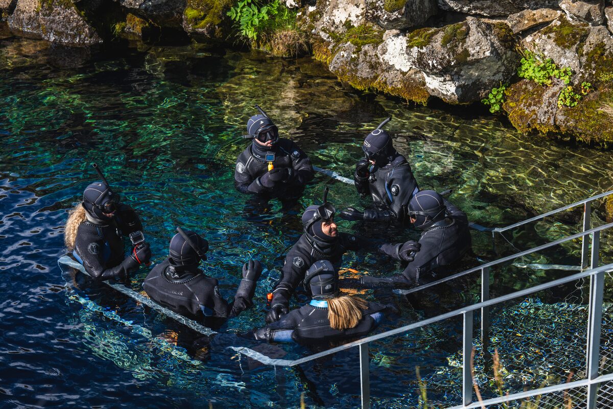 Group of tour guides with small group of tourists entering the waters at Silfra, Thingvellir for a snorkeling tour.