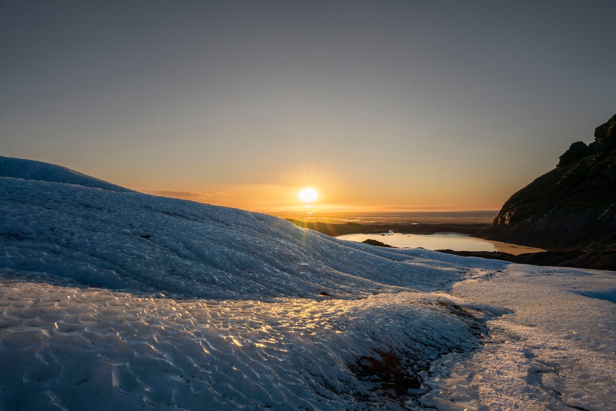 Midnight sun high in sky shining over Falljokull glacier in Iceland in summer.