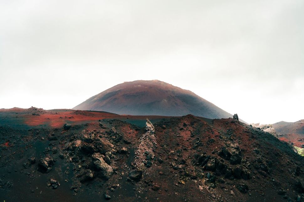 Red ash and dirt covered Heimaey island volcano.